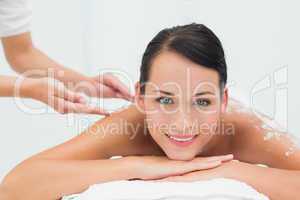 Peaceful brunette getting a salt scrub beauty treatment