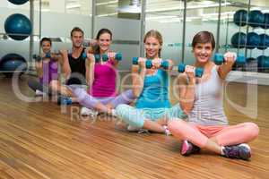 Fitness class sitting and holding dumbbells