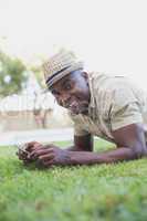 Smiling man relaxing in his garden texting on phone