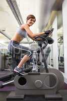 Fit smiling woman working out on the exercise bike