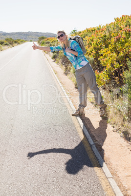 Attractive blonde hitch hiking on rural road