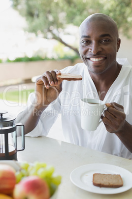 Handsome man in bathrobe having breakfast outside