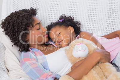 Cute daughter sleeping with mother on the sofa