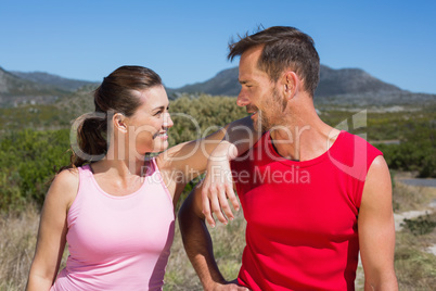 Active couple standing on country terrain smiling at each other