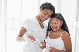 Pretty mother brushing her teeth with her daughter