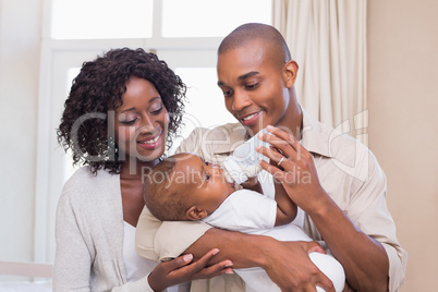 Happy parents feeding their baby boy a bottle