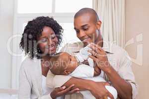 Happy parents feeding their baby boy a bottle