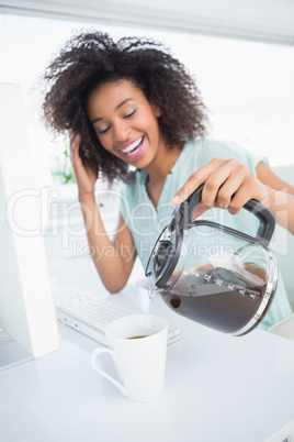 Tired businesswoman pouring a cup of coffee at desk