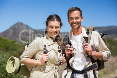 Hiking couple standing and smiling at camera on country terrain