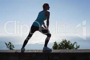 Fit woman stretching her legs looking out to sea