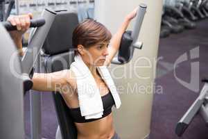 Serious brunette using weights machine for arms