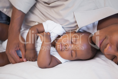 Father napping with baby son on couch