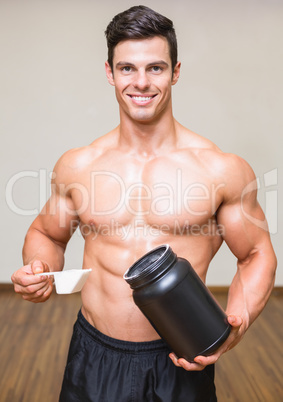 Body builder holding a scoop of protein mix in gym