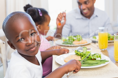 Family enjoying a healthy meal together with son smiling at came