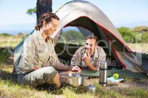 Outdoorsy couple cooking on camping stove outside tent