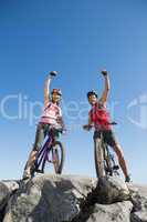 Fit cyclist couple cheering at the summit