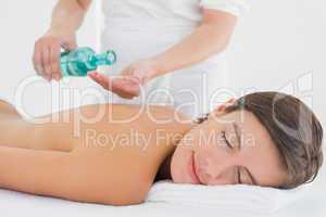 Attractive woman getting massage oil on her back