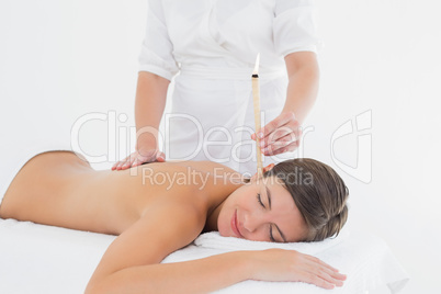 Beautiful woman receiving ear candle treatment at spa center