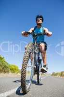 Athletic man cycling on open road