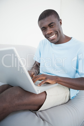 Casual man sitting on sofa using laptop