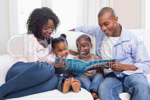 Happy family on the couch reading storybook