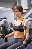 Focused brunette using weights machine for arms