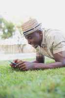 Smiling man relaxing in his garden texting on phone