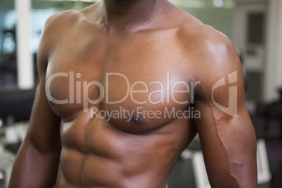 Mid section of a muscular shirtless man in gym