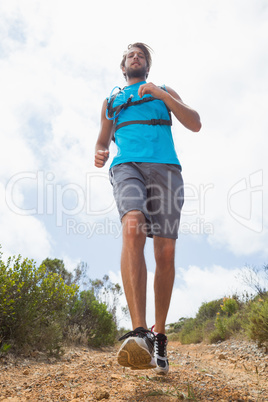 Fit man jogging down mountain trail