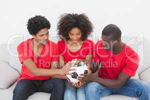 Football fans sitting on couch holding ball