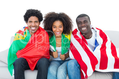 Happy football fans wrapped in flags smiling at camera
