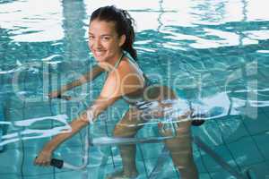 Fit brunette using underwater exercise bike