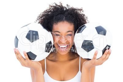 Pretty girl holding footballs and laughing at camera