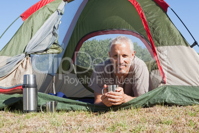 Happy camper smiling at camera lying in his tent