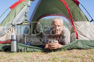 Happy camper smiling at camera lying in his tent