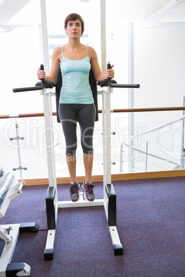 Fit brunette supporting her weight on bars