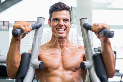Muscular man working on fitness machine at the gym