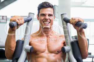 Muscular man working on fitness machine at the gym