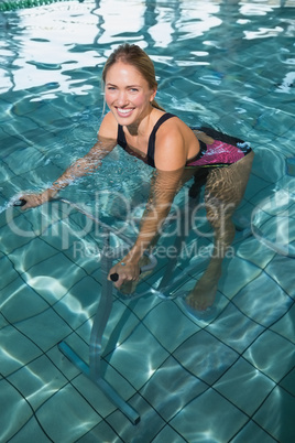 Fit happy blonde using underwater exercise bike