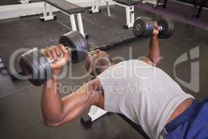 Muscular man exercising with dumbbells