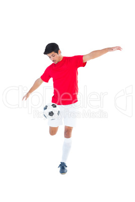 Football player in red kicking ball