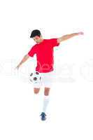 Football player in red kicking ball