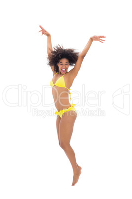 Fit girl in yellow bikini jumping and smiling at camera