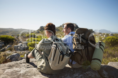 Hiking couple sitting on mountain terrain