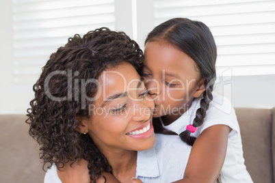 Pretty mother sitting on the couch with her daughter kissing her