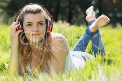 Pretty blonde lying on grass listening to music