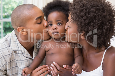 Happy couple on bed with baby daughter