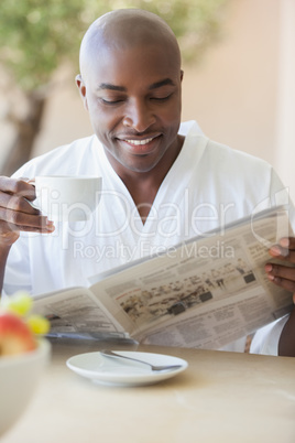 Happy man in bathrobe having coffee on terrace