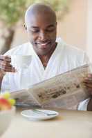 Happy man in bathrobe having coffee on terrace