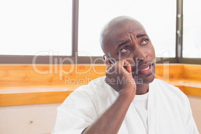 Serious man in bathrobe talking on phone